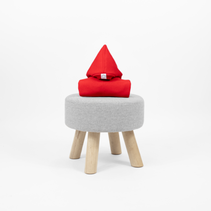 Red shark jumpsuit with a pointy hood displayed on a little chair.
